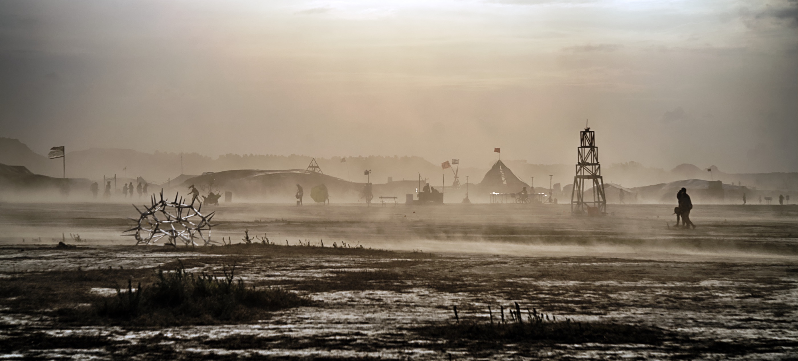 The lighthouse on the playa during a sandstorm, people walking past