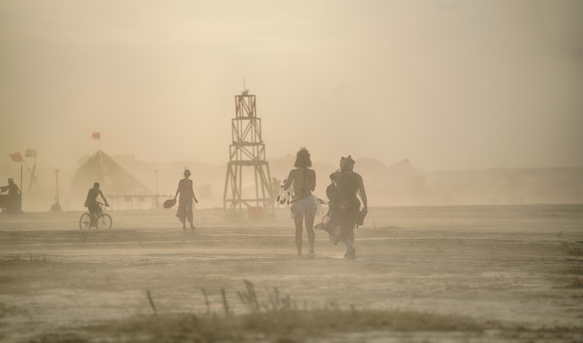 People walking through a sandstorm, the lighthouse in the distance