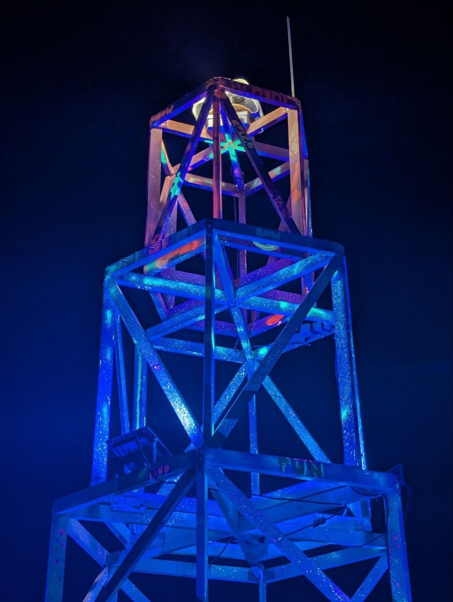 The lighthouse glowing blue at night