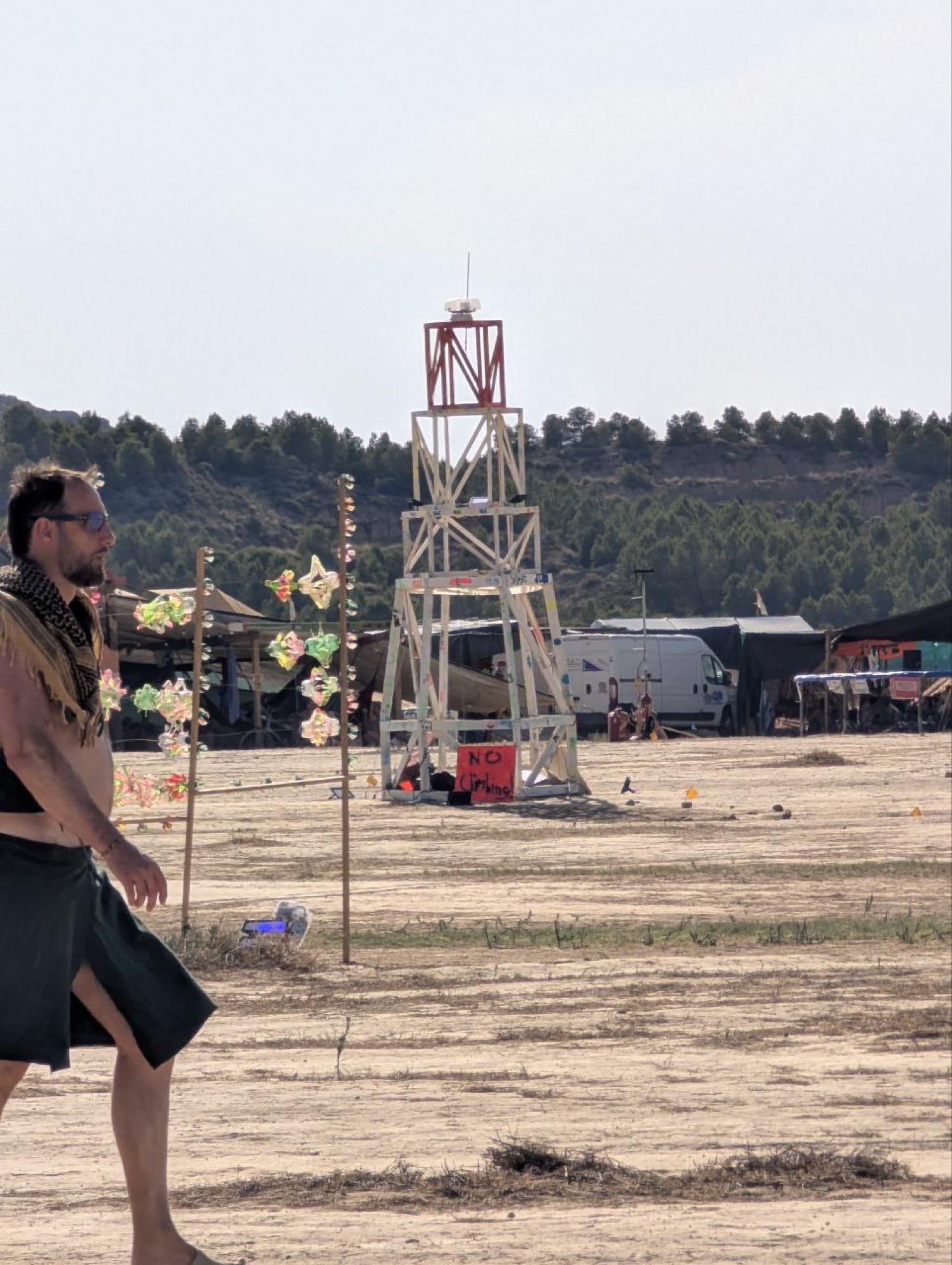 A person on the playa by day, the lighthouse behind them